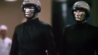 Two android policemen with silver heads and dark uniforms in THX 1138