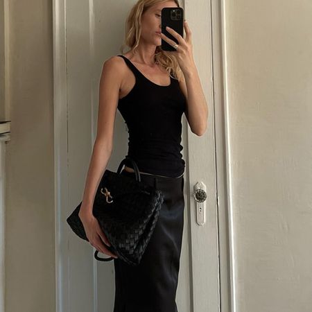 Elly McGaw wearing a black tank top, black-and-white layered Sportmax skirt, black heels, and a black Bottega Veneta Andiamo bag.