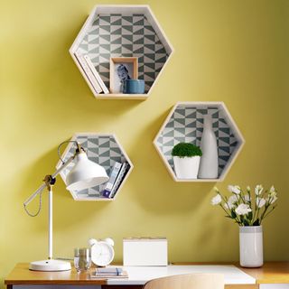 Home office with yellow walls and hexagonal open shelving cubbies