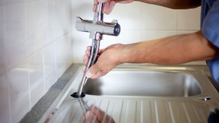 Chrome mixer tap being fitted into single hole sink 