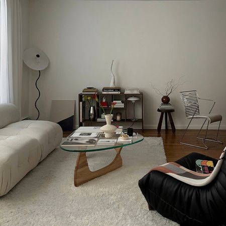 a living room with a white coach black toga chair and glass coffee table