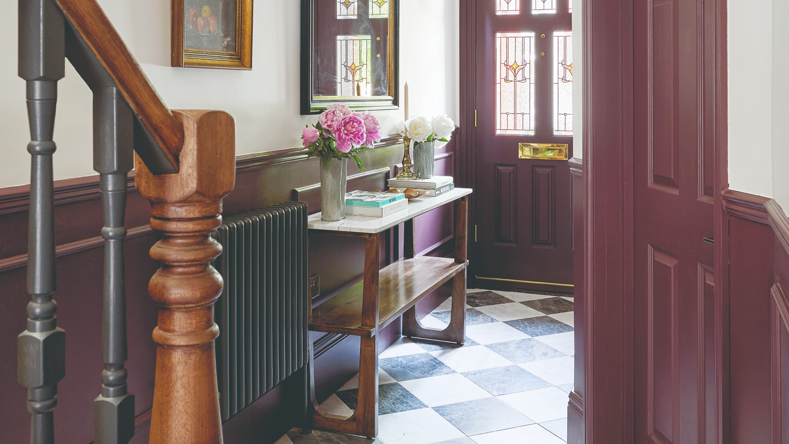 A narrow hallway with the bottom half of the wall covered in wall panelling and painted in burgundy and the top painted white