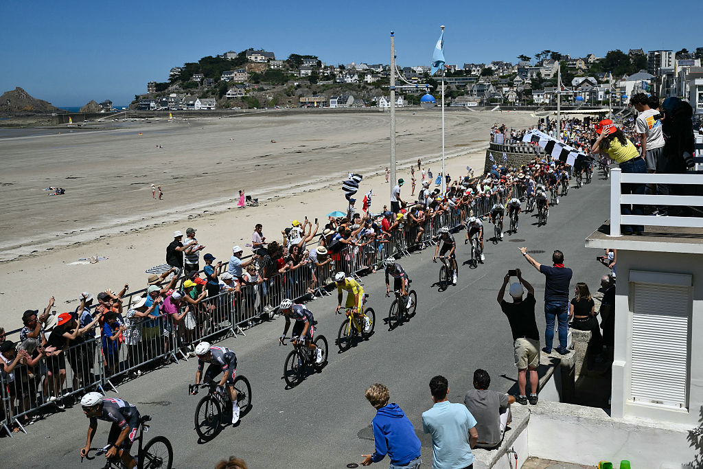 Alpecin - Deceuninck team's Dutch rider Mathieu van der Poel wearing the overall leader's yellow jersey cycles with the pack of riders (peloton) along the waterfront in Pleneuf-Val-Andre during the 7th stage of the 112th edition of the Tour de France cycling race, 197 km between Saint-Malo and Mur-de-Bretagne Guerledan, in Brittany, western France, on July 11, 2025. (Photo by Marco BERTORELLO / AFP)