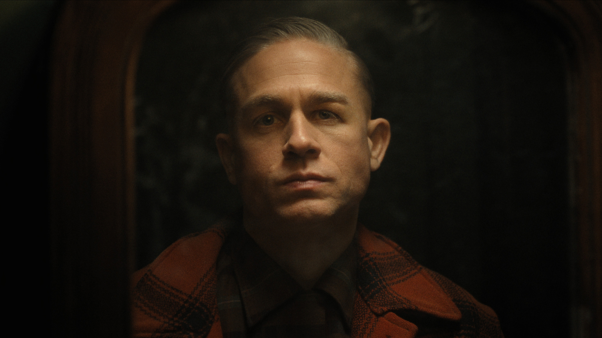 charlie hunnam wearing a plaid shirt as ed gein in a still from monster