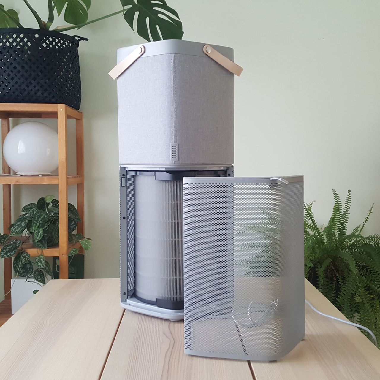 The AEG AX91-604GY Connected Air Purifier being tested in a room with green walls and a wooden table