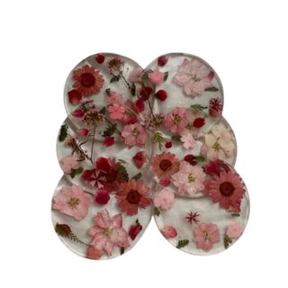 6 circular resin pressed flower coasters with dark pink and dull pink flowers.