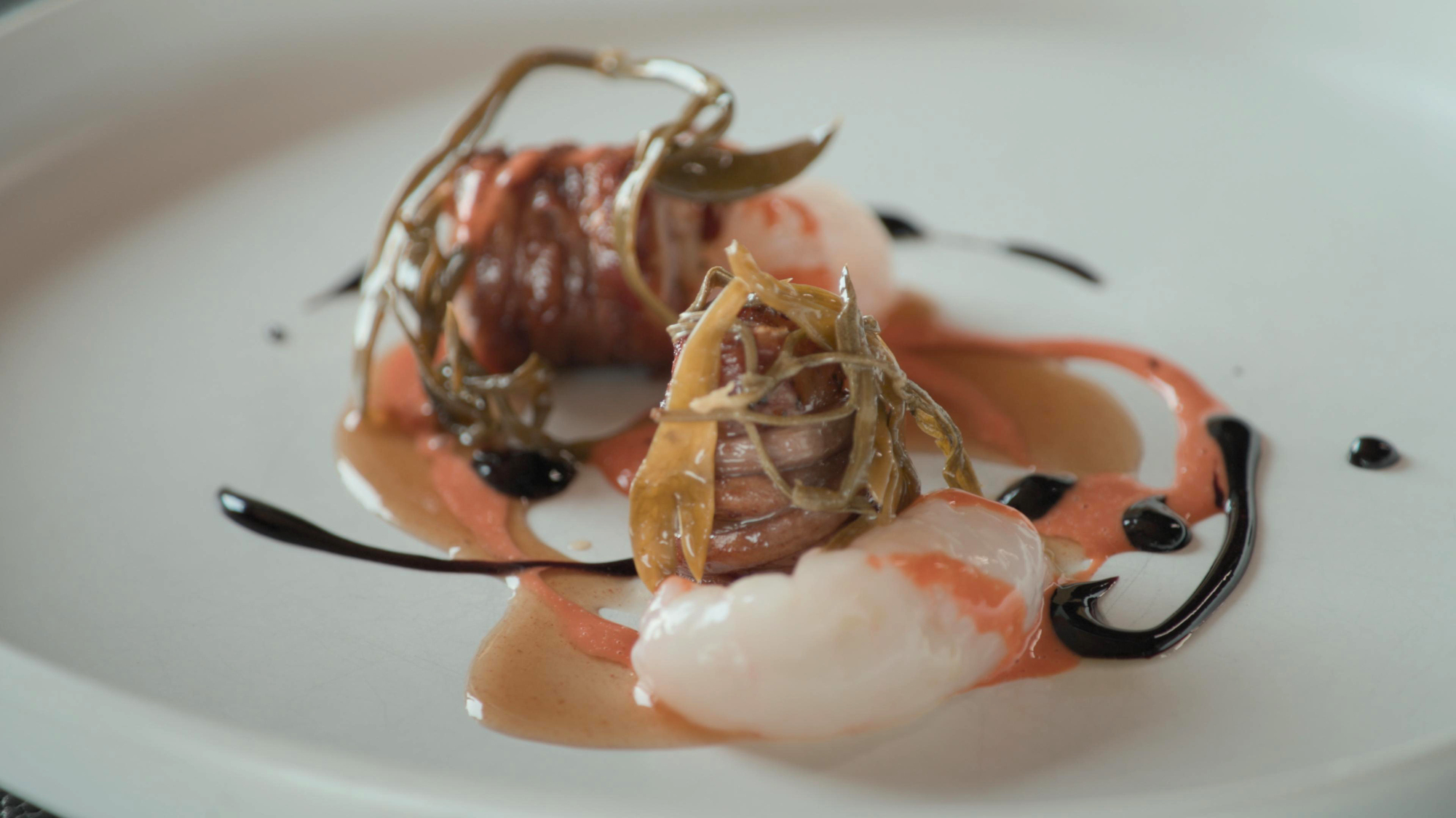 Torcinello, a traditional sausage, served with scampi, sea asparagus, and sweet pepper sauce