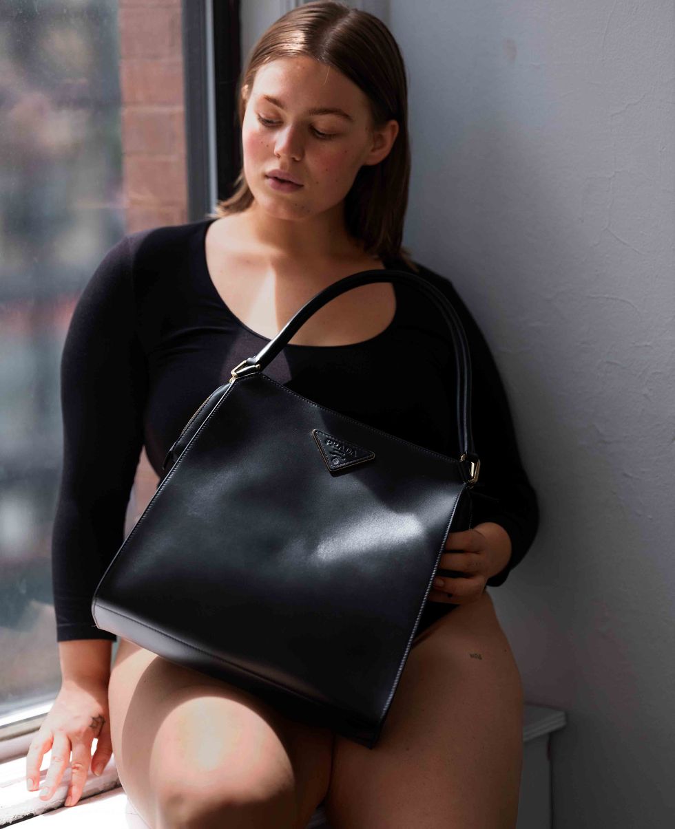Model sat on window sill holding handbag