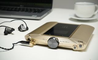 iFi iDSD Valkyrie in gold, on a beige desk