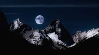 A photograph of a full moon above mountains, taken in New Sarepta, a hamlet in Alberta, Canada.