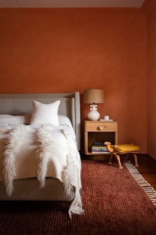 Bedroom with terracotta walls, pink ceiling and beige bed