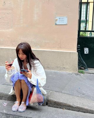 a woman sitting on a curb wearing jelly sandals