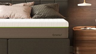 Emma Diamond Hybrid with branding on a bed frame with pillows