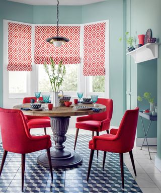 Red and blue dining room, round vintage antique table, red chairs, patterned floor tiles