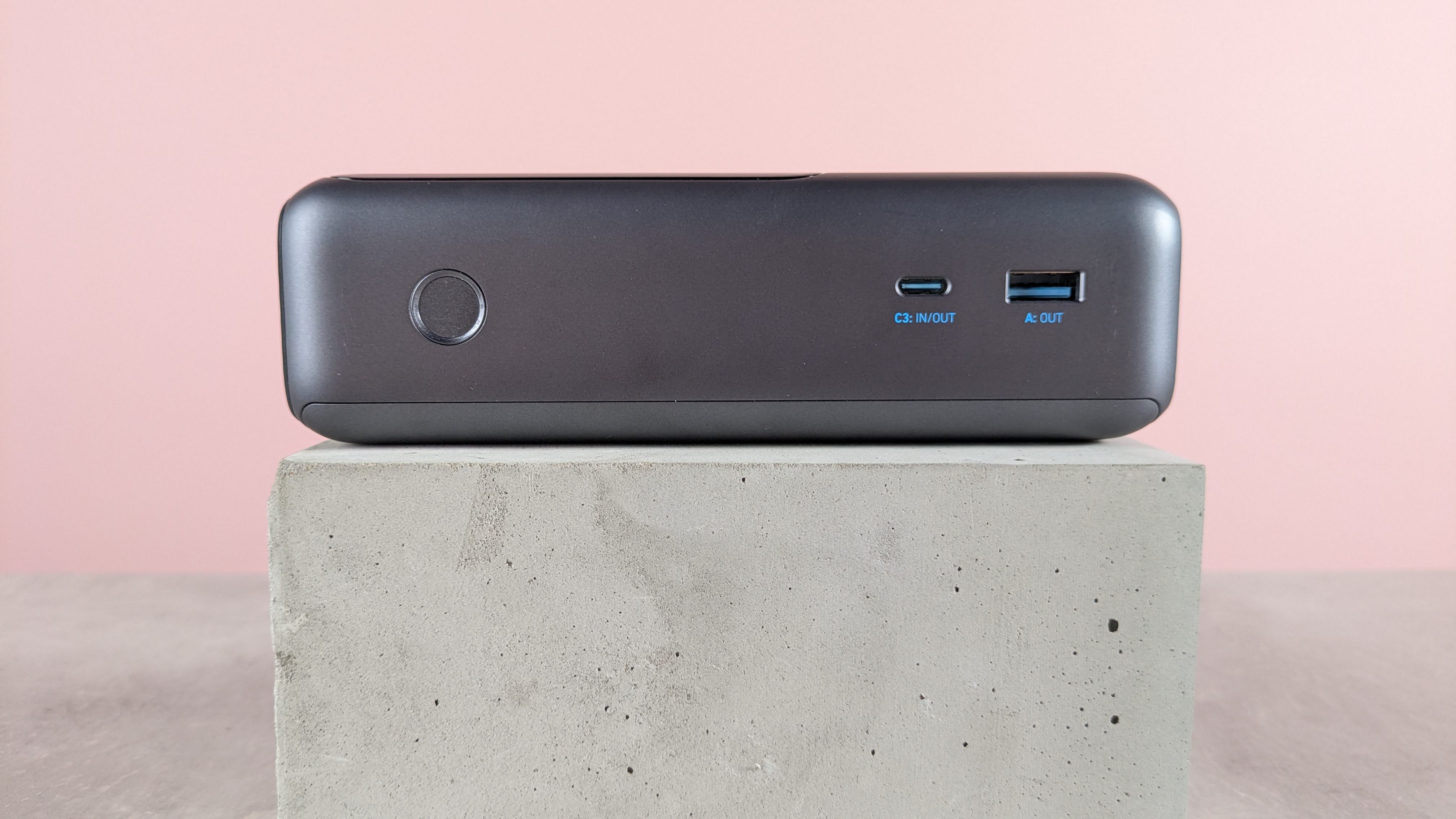 Side view of Anker Laptop Power Bank on desk with pink background