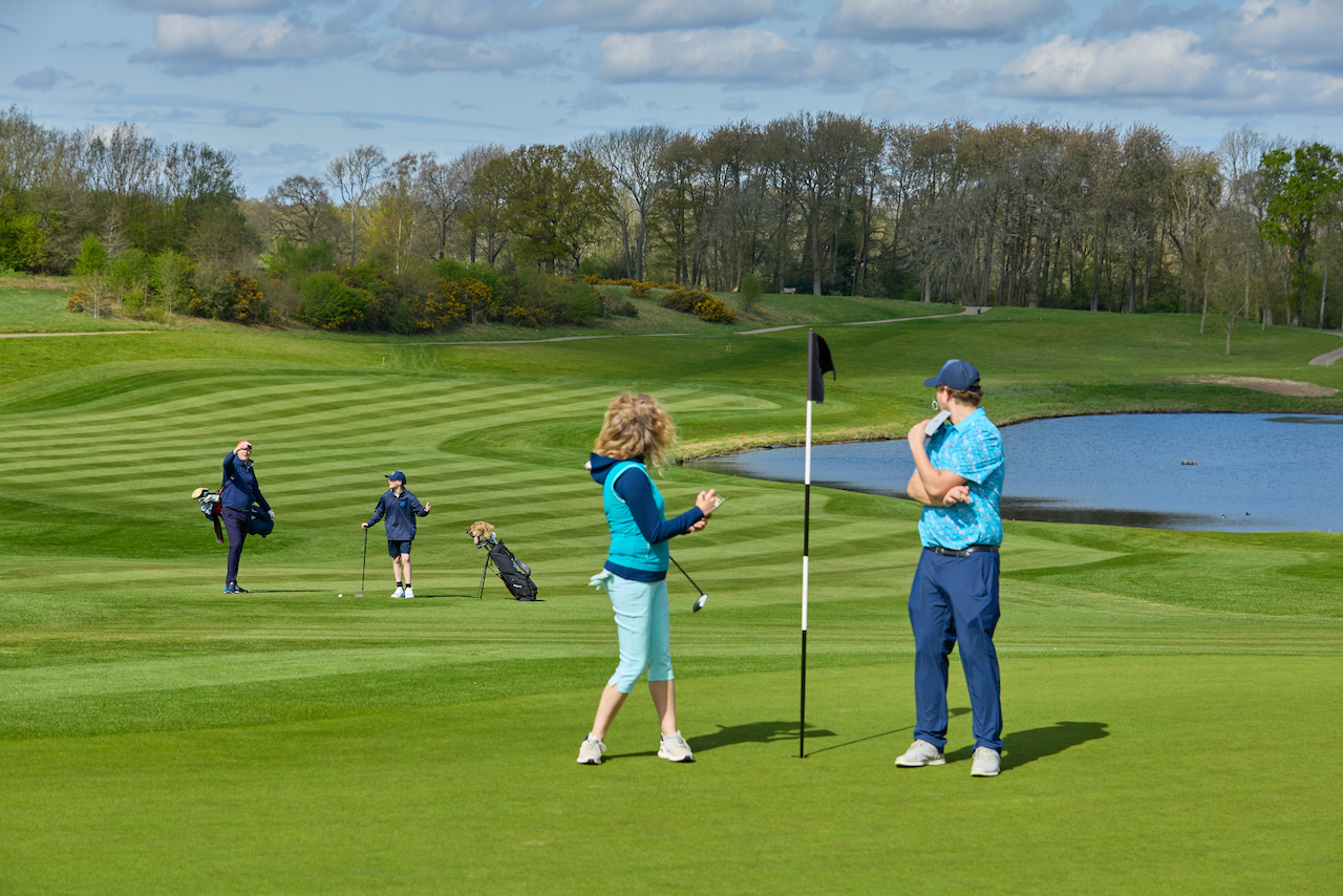 Two golfers not getting off the green quickly after playing which holds up the group behind and impacts pace of play
