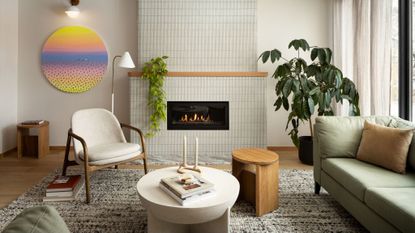 living room with tiles fireplace, white accent chair, colorful art, plants, white coffee table