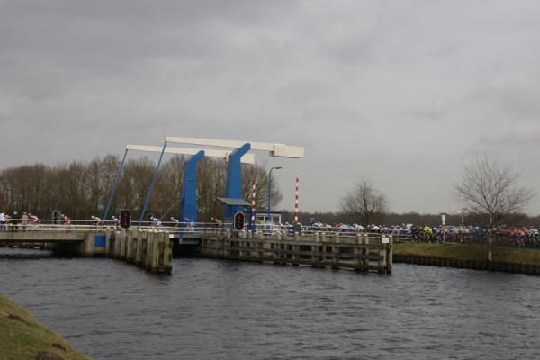 The peloton heads over one of the distinctive bridges of the region