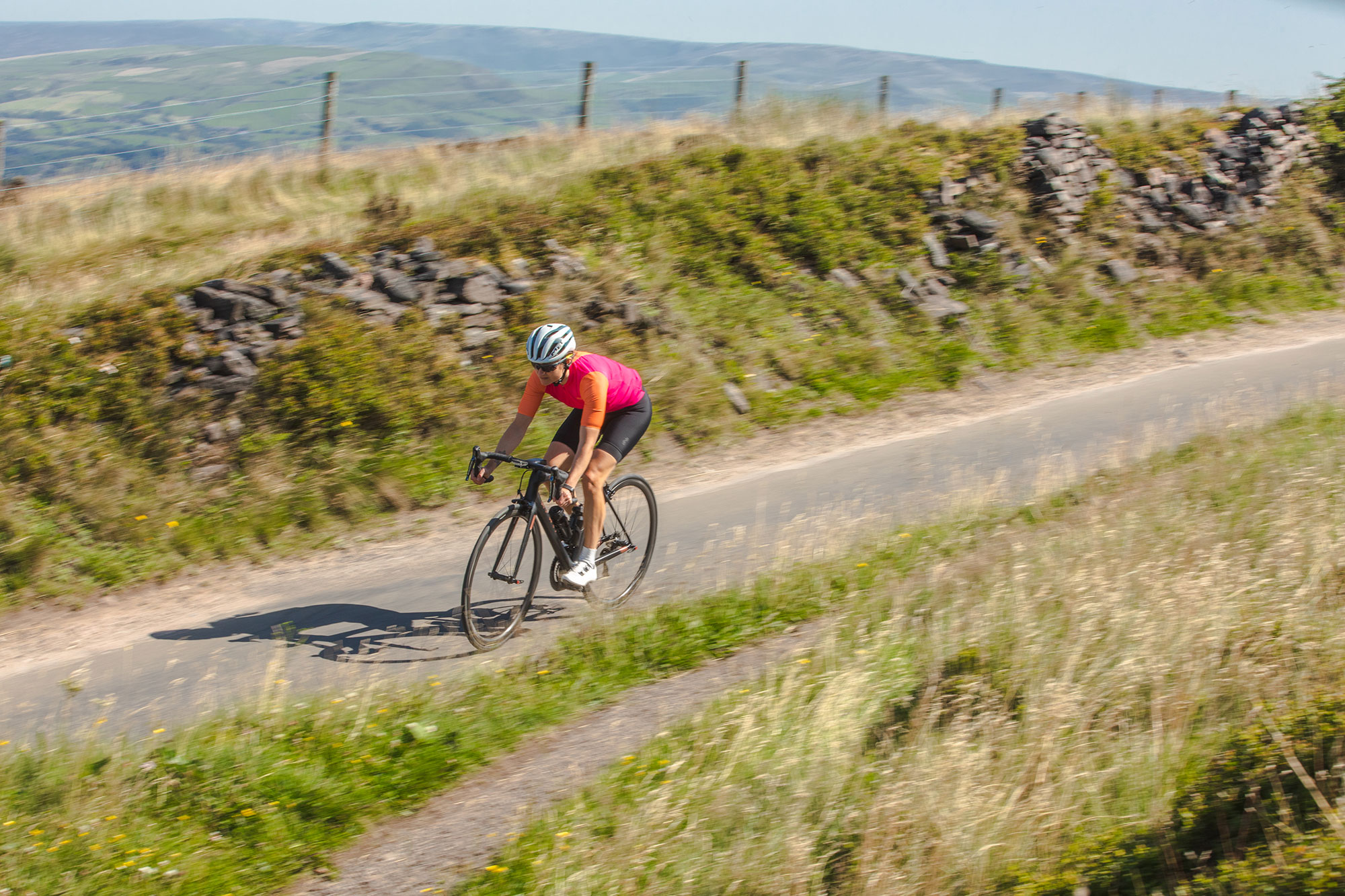 Woman cycling fast along country road in Peak District