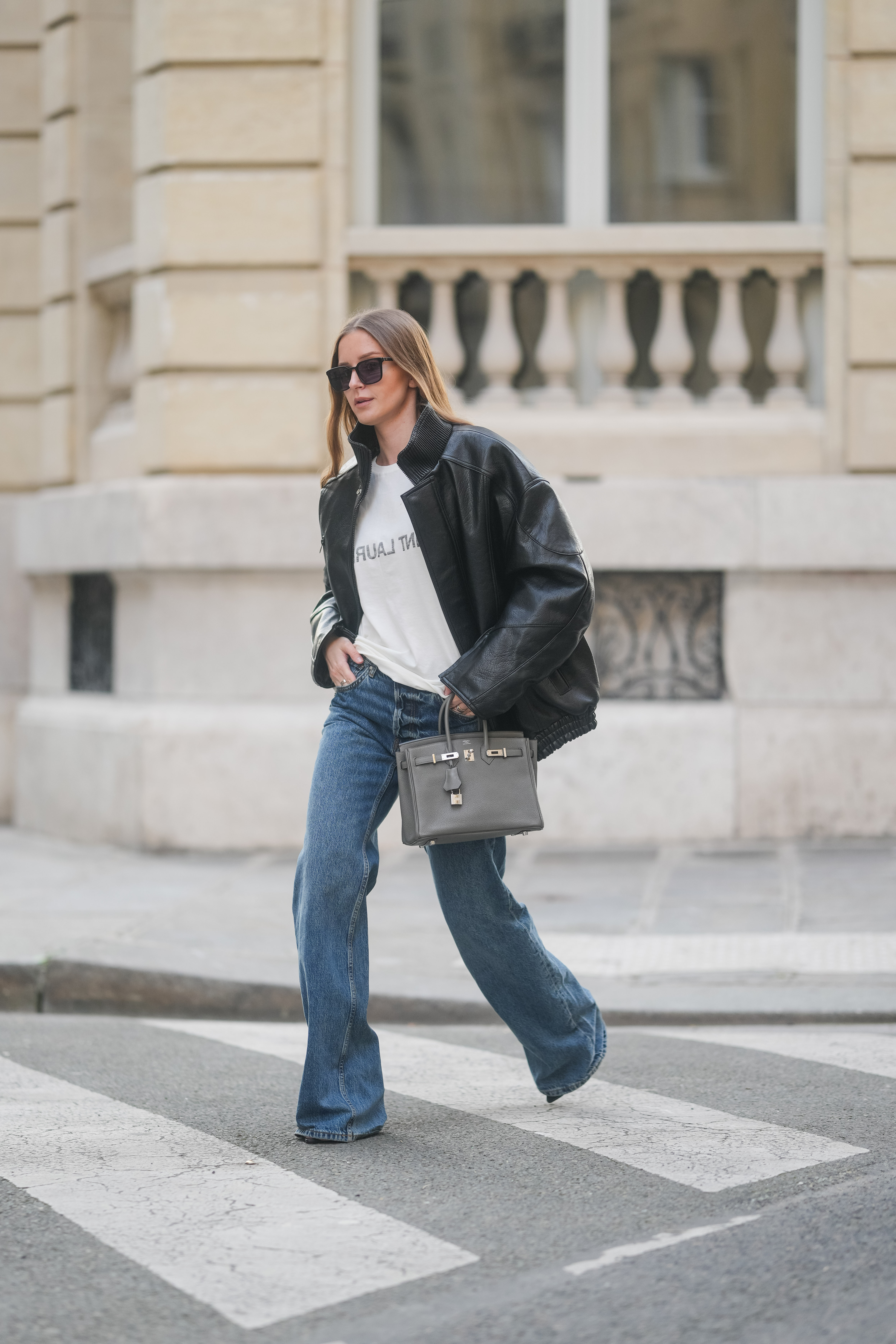woman wearing a slogan T-shirt and a leather jacket with flared jeans