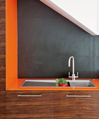 kitchen room with orange and black wall and kitchen sink
