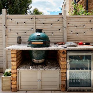 Outdoor kitchen with Big Green Egg, drinks fridge and festoon lights