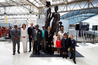 Britain's Prince William (3rdL), Duke of Cambridge, Britain's Catherine (2ndL), Duchess of Cambridge, Baroness Floella Benjamin (R), Windrush passengers Alford Gardner (C) and John Richards (4thL) and children pose for a picture with the National Windrush Monument created by Jamaican artist Basil Watson (L) at Waterloo Station in London on June 22, 2022