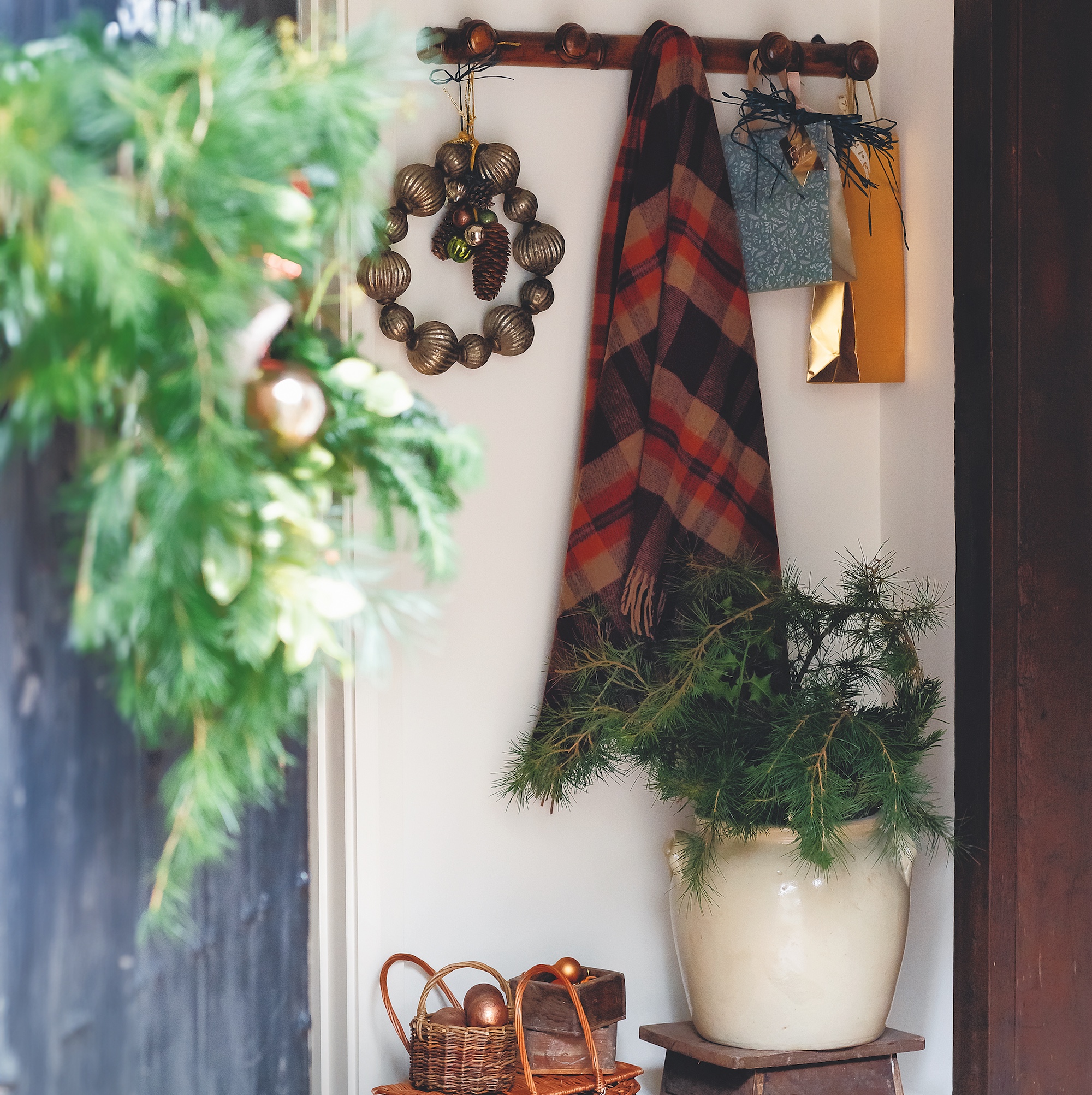 entranceway with wooden peg rail hung with wreath made from gold baubles