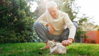 Man brushing cat in the garden