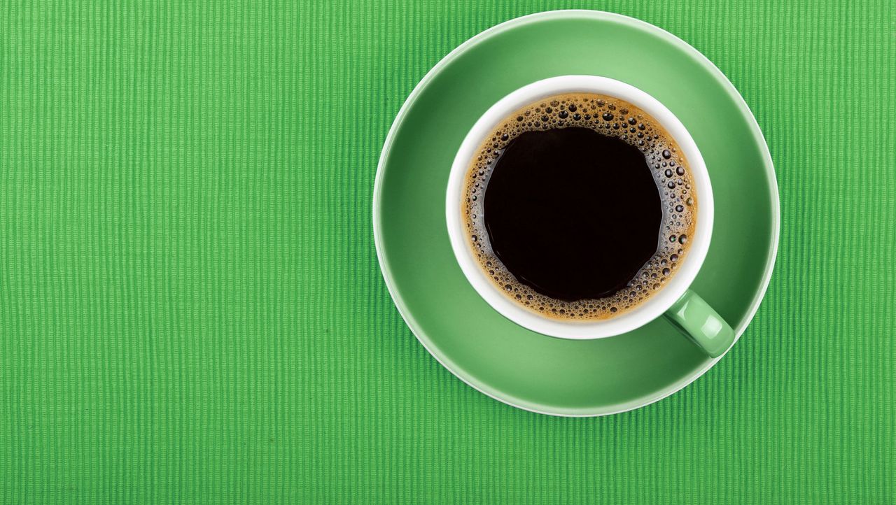 Full black coffee in green cup close up top view