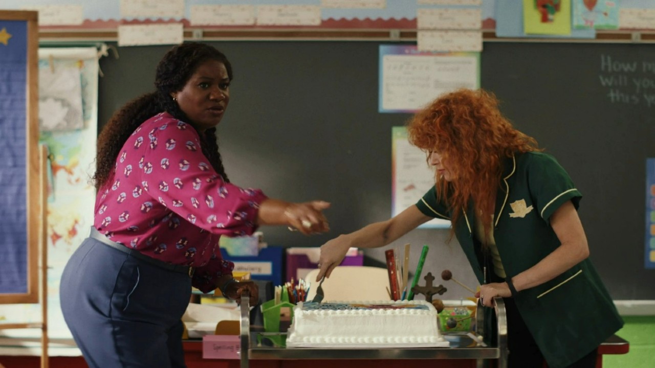 Natasha Lyonne cuts a cake while talking to Adrienne C. Moore in Poker Face.