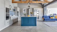 An open-plan kitchen with grey cabinetry, blue kitchen island with blue living room sofa