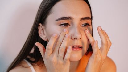 woman applying eye cream under eyes