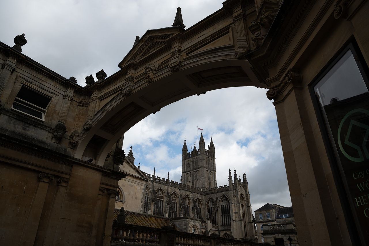 Bath Abbey against a blue sky, framed by an ornate arch