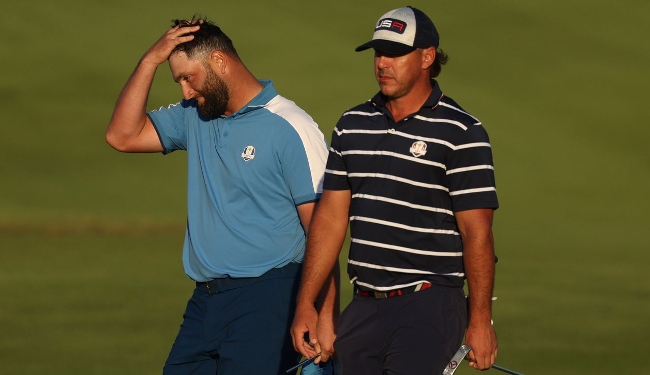 Jon Rahm and Brooks Koepka walk alongside each other on the 18th green