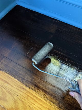 gel stain being applied to a wood floor with a paint roller