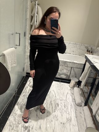 woman wearing a black off the shoulder dress in a bathroom