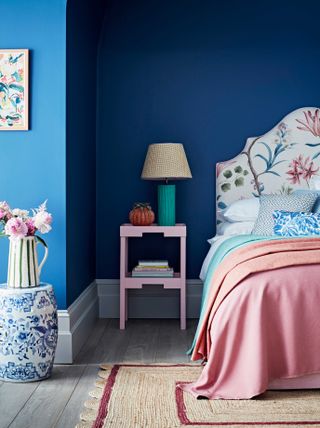 blue cobalt bedroom wall with pastel coloured bedspread and upholstered bedframe