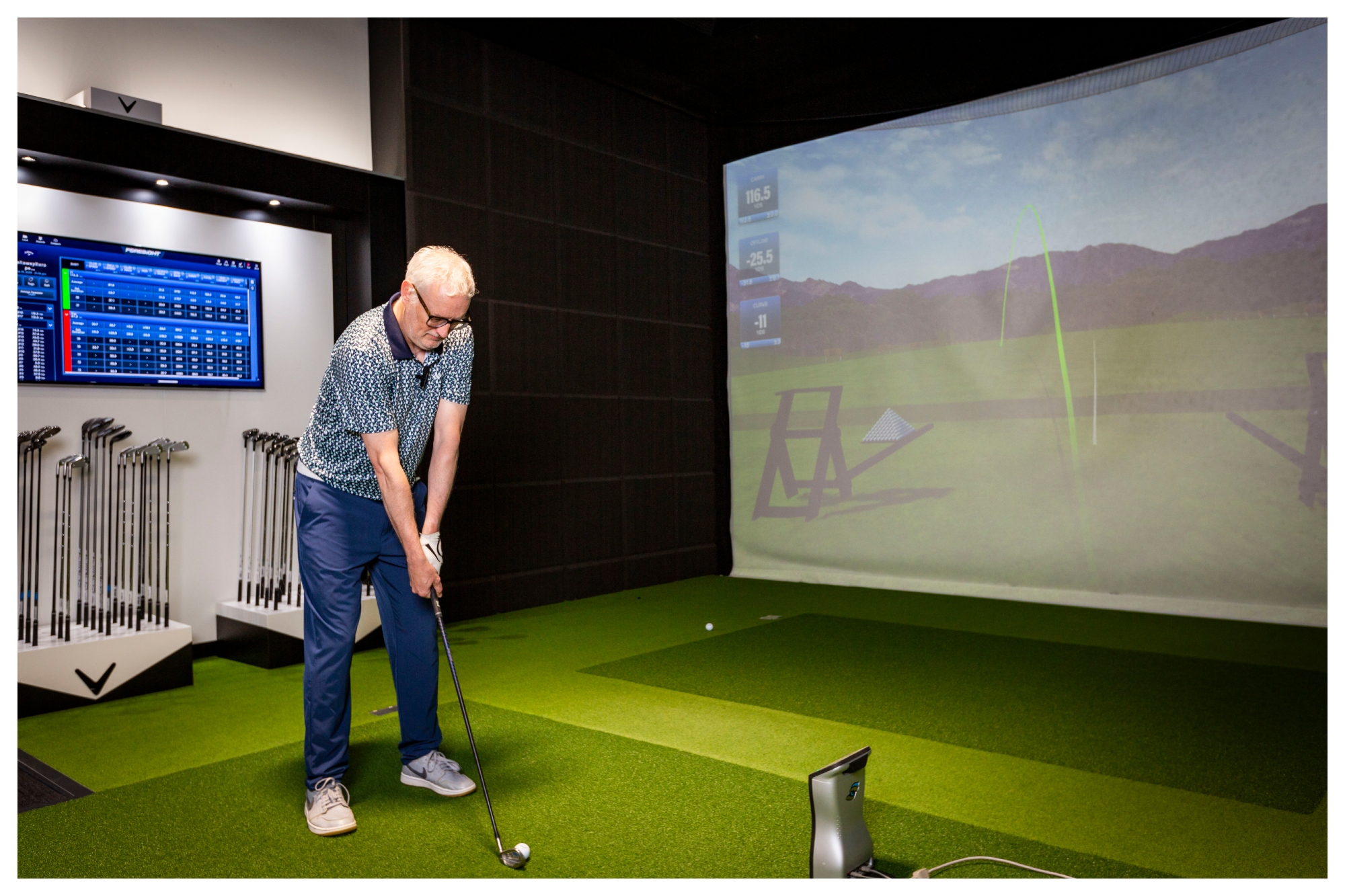 A middled-aged man addresses a the ball at a Callaway golf club fitting session