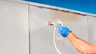 Hand spraying a fence in white