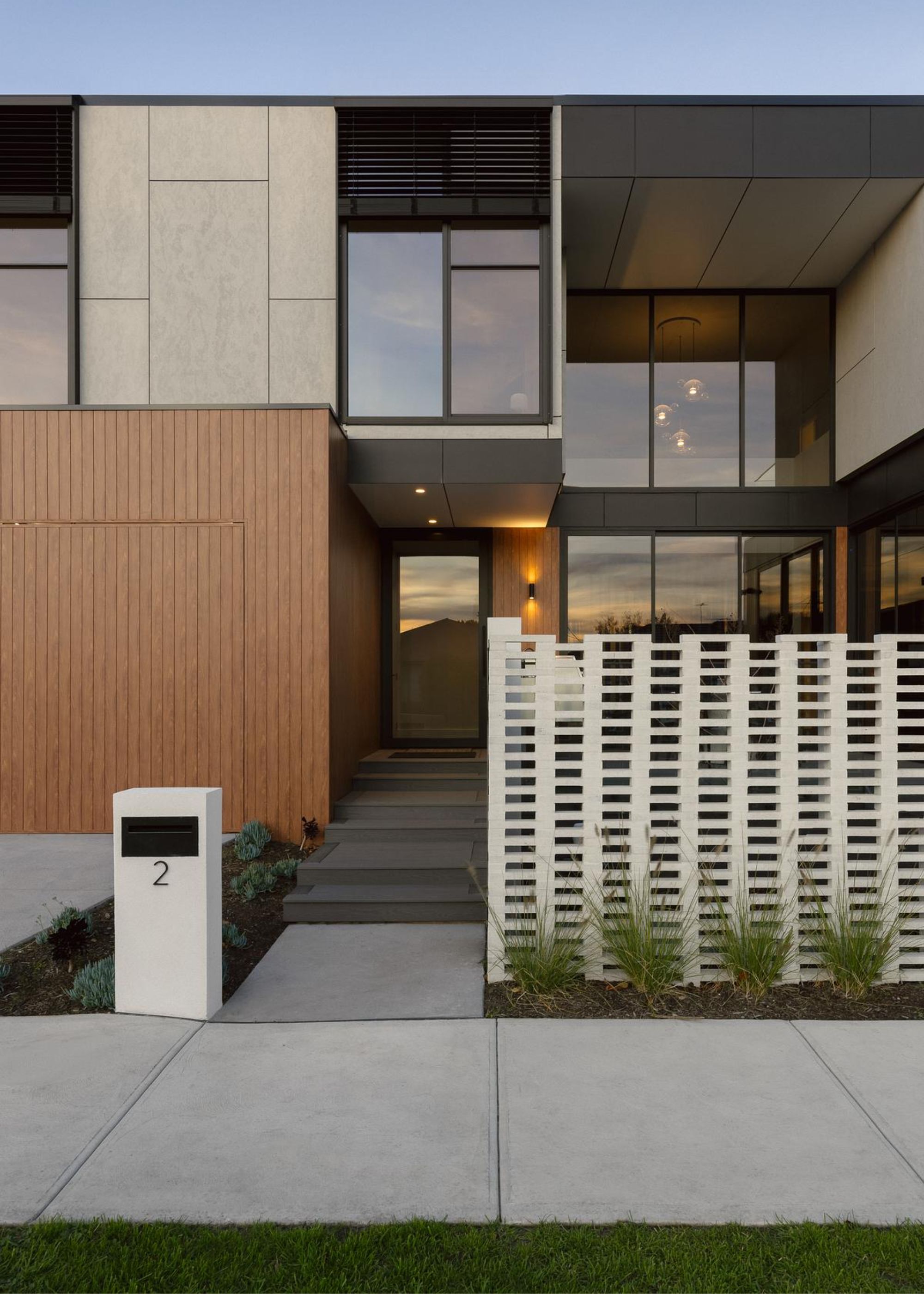 The exterior of a home with anthracite windows and doors as well as a white brick fence and a small white letter box on the side