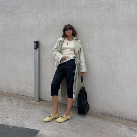 Influencer Emilie T wearing a trench coat, capri pants and ballet flats. 