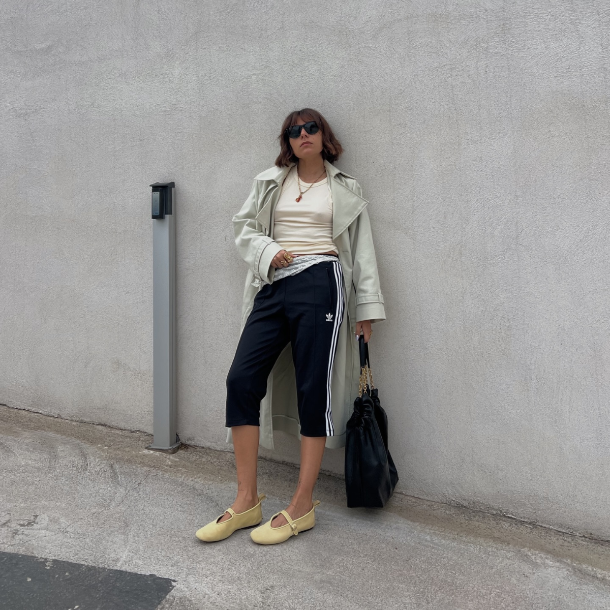 Influencer Emilie T wearing a trench coat, capri pants and ballet flats. 