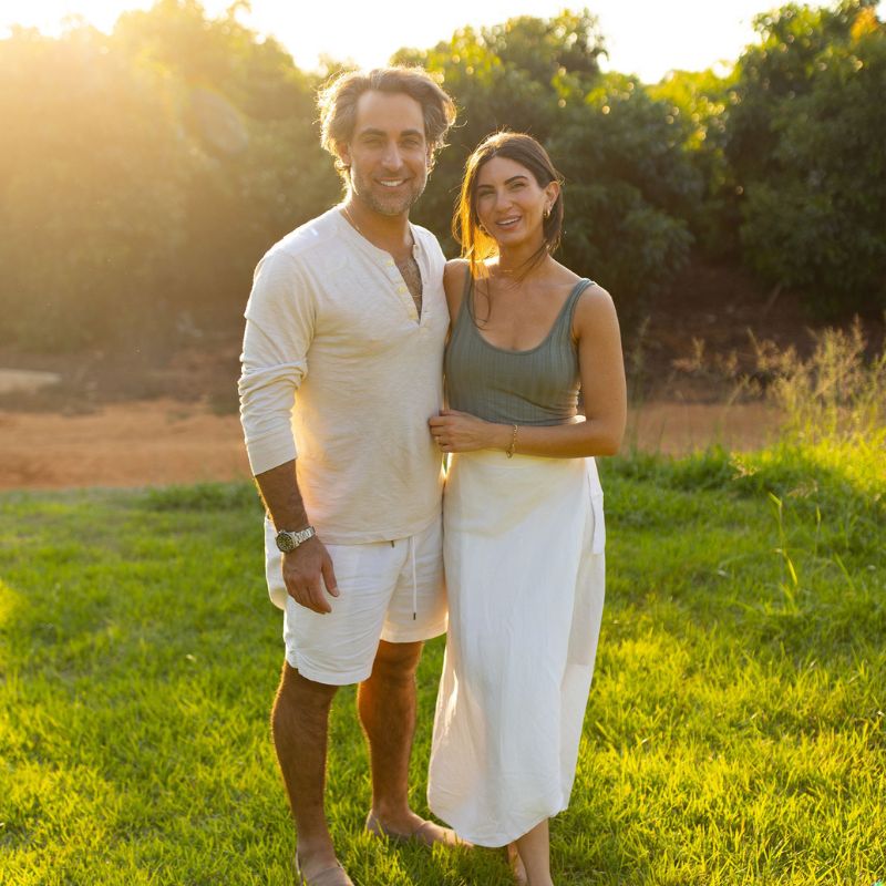 couple standing outside on green lawn with the sun setting