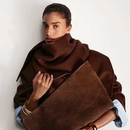 model holding a chocolate brown suede handbag