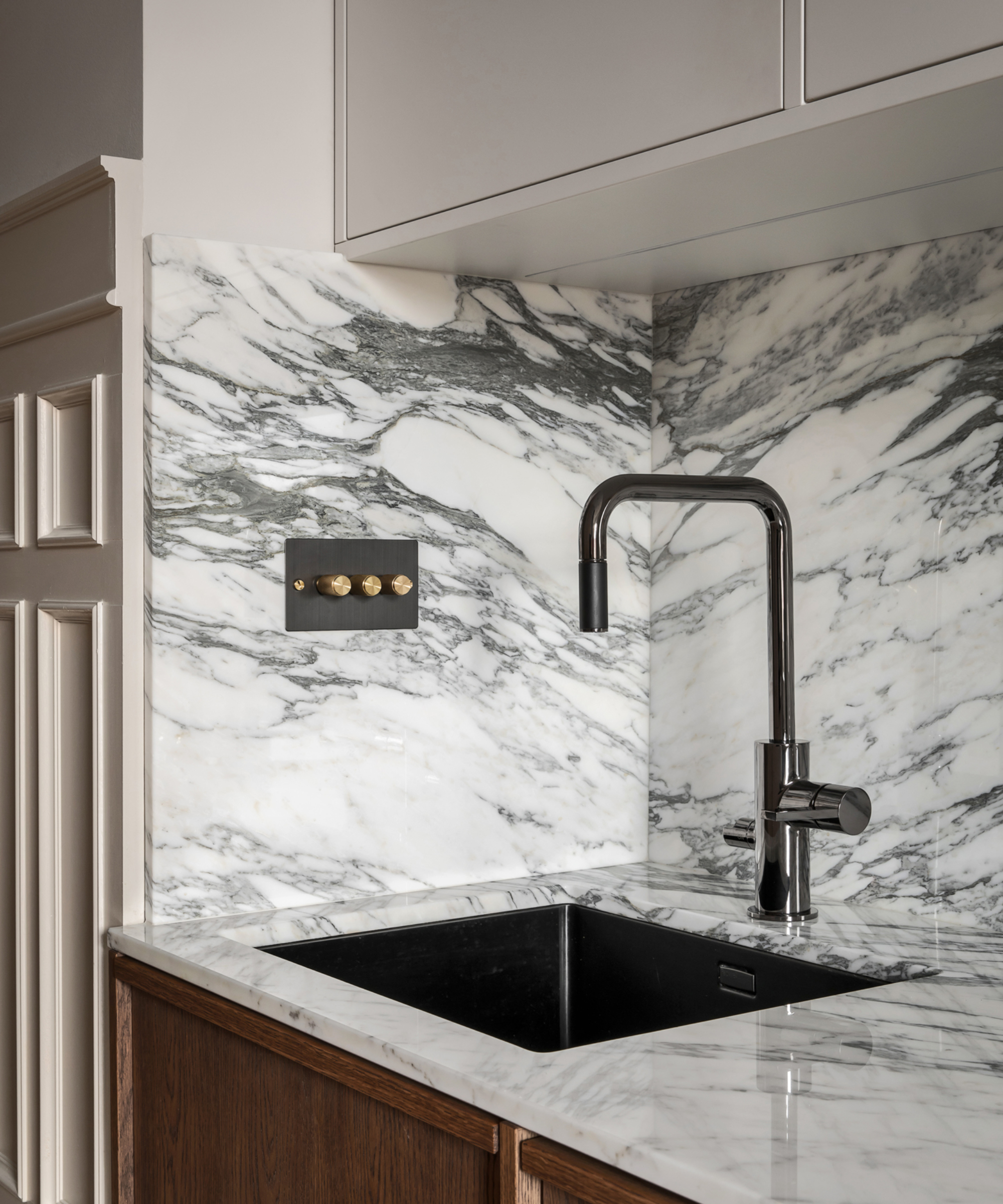 dimmer light switch with black nickel and gold finish in kitchen with marbled splashback and work top