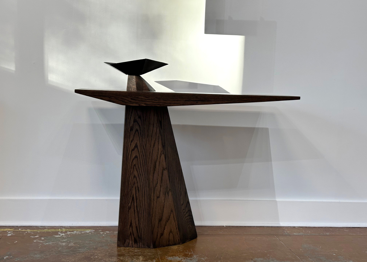 A wood table with a burner bowl in a white room with stone flooring