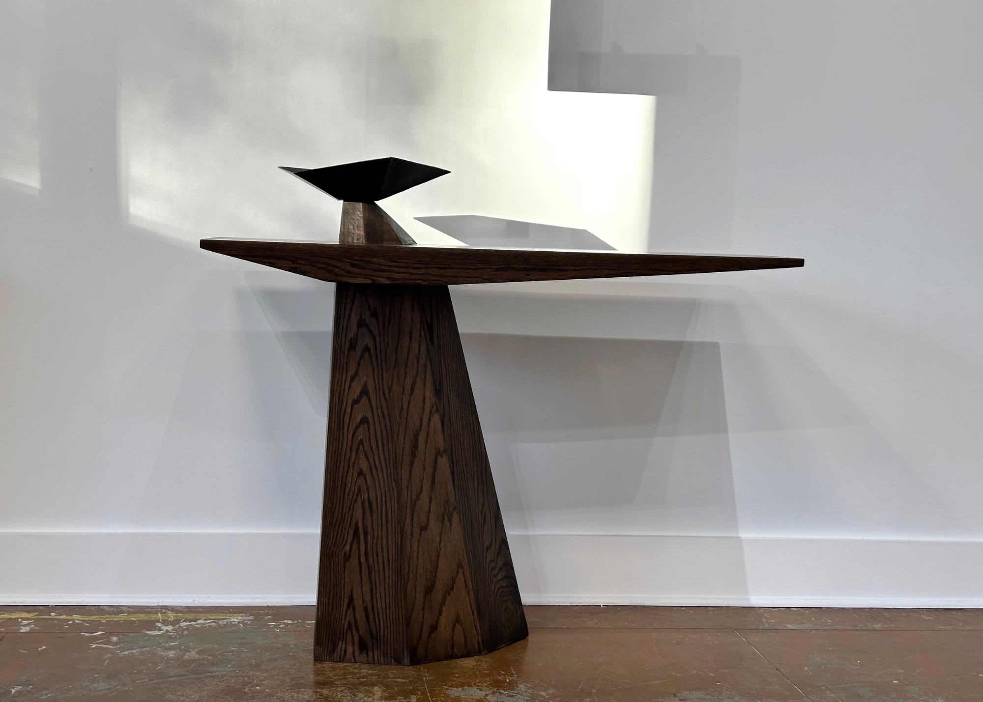 A wood table with a burner bowl in a white room with stone flooring