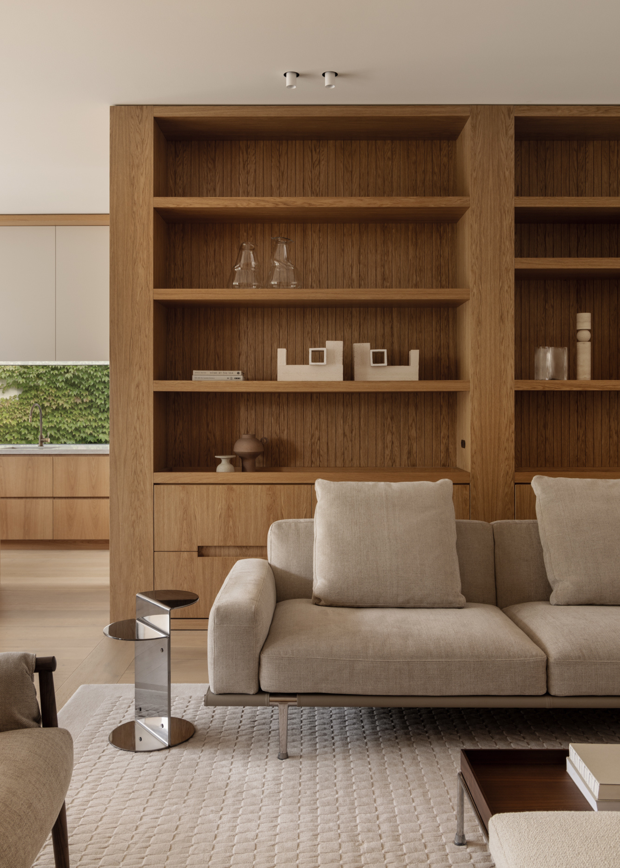 A living room with a wood storage cabinet, a beige couch, a silver side tale, and a wood coffee table