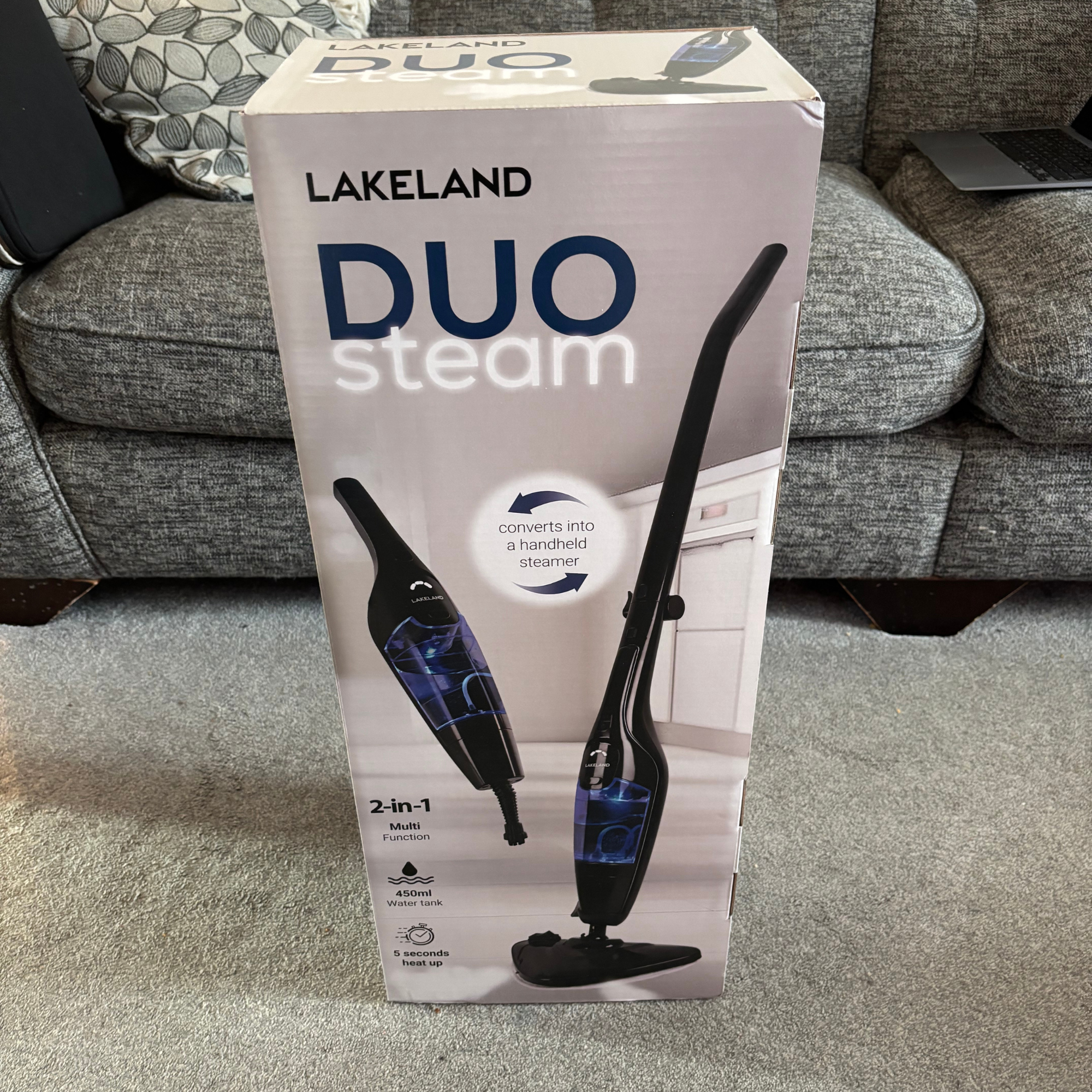Lakeland 2-in-1 Steam Mop packaging placed upright in front of sofa